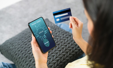 Woman holding smartphone and credit card with scanning biometric fingerprint for approval to access for payment mobile banking on application wallet.