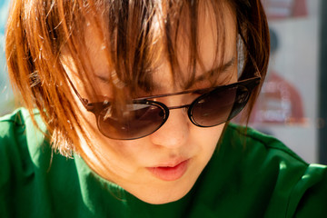 A fashionable young woman in sunglasses looking down