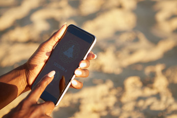 Woman pausing yoga session on smartphone after finishing working out on the beach