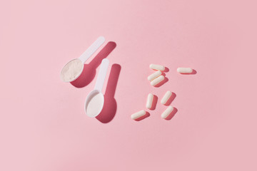 Protein powder, scoop, energetic musli bars, vitamin pills, gainer on pink background with shadow - concept of sport diet, healthcare, nutrition fit fitness food, copyspace