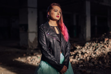 Portrait of a young girl with pink hair standing next to the bricks in a collapsed building