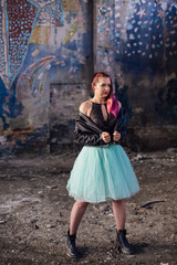 Portrait of a young girl with pink hair standing inside of collapsed building surrounded by ruins