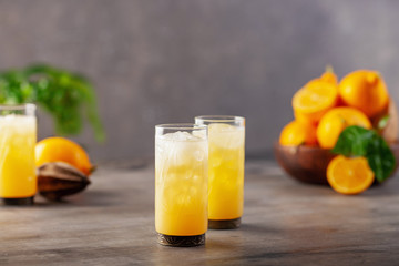 Limoncello in glass, sweet Italian lemon liqueur, traditional strong alcoholic drink and lemons on the blue background.