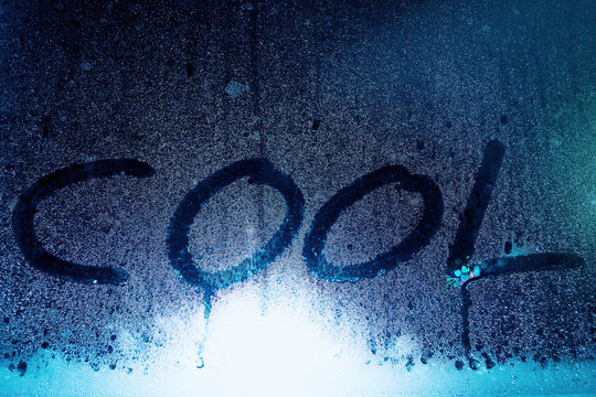 Cool word written on the wet window glass highlighted by blue neon lights. Handwritten message. Season symbol - Powered by Adobe