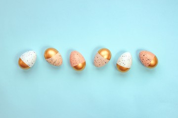 Top view of easter eggs colored with golden paint and different colors. Blue background. Copy space.