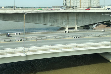 Transportation aeriel image of elevated expressway and superhighway bridge across the river in suburb area of Bangkok Thailand with moving automobiles.