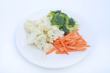 Cauliflower, broccoli and carrots on a plate isolated on white background.