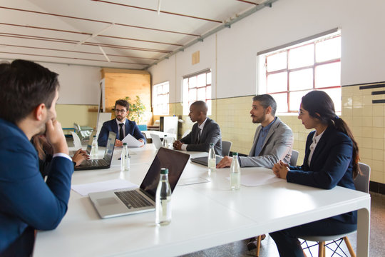 Group of concentrated marketing experts during morning briefing. Focused workers sitting at table and discussing some business issues. Business meeting, teamwork concept