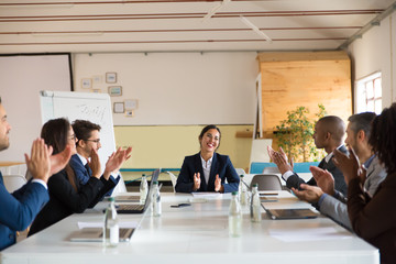 Subordinates applauding successful Asian speaker. Group of smiling business people during morning briefing. Business meeting concept