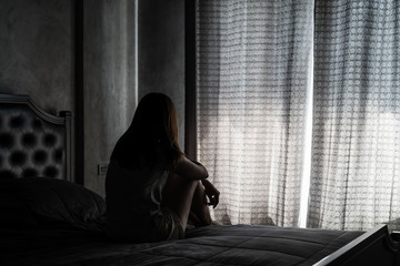 Fototapeta Lonely young woman feeling depressed and stressed sitting head in hands in the dark bedroom, Negative emotion and mental health concept obraz