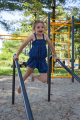 Fototapeta premium Young girl in a blue dress on a playground