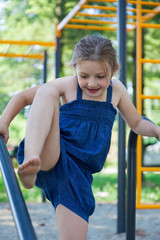 Fototapeta premium Young girl in a blue dress on a playground