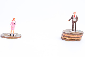 Gender pay gap concept with miniature and coins on white background. World request equal payment...