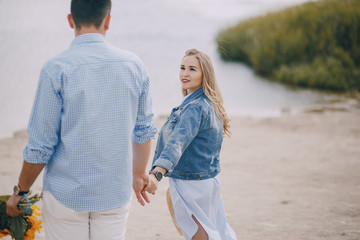 beautiful long-haired blonde with her handsome man wallkinh near water on the beach