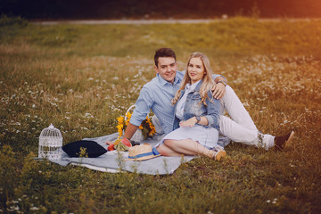 beautiful long-haired blonde with her handsome man sitting in the park with fruits