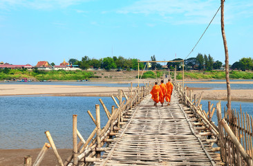 Three buddhist monks on bamboo bridge across Mekong, Kampong Cham, Cambodia