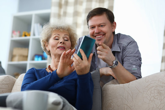 Elderly mother shows photo in phone to adult son. Adult mother shows her son his page on social network. Elderly lady shares her observations with relative while traveling. Respect for strakhs