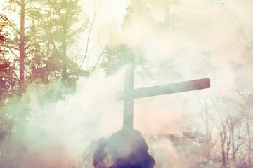Burning catholic cross in puffs of smoke (vintage filter).  Fire Burning Cross 