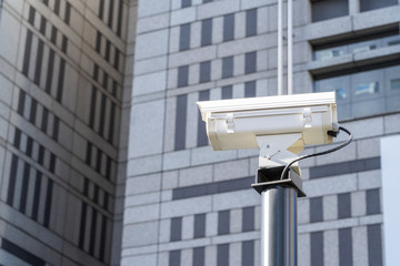 CCTV camera on a street and building on background. Concept of IOT surveillance and monitoring.