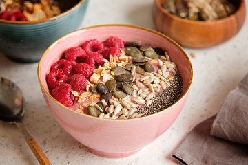Healthy food - smoothie bowl topped with raspberries, granola, seeds and chia. Closeup view