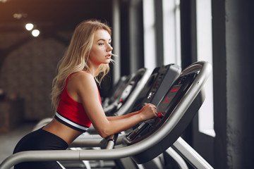 Fototapeta na wymiar Girl in a gym. Woman on a racetrack. Lady in a red top.