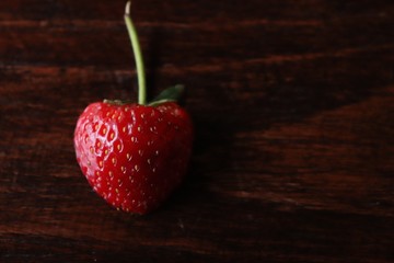 Red half strawberry on wood table for the seasonal fruit in winter