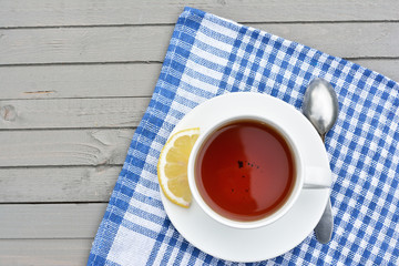 cup of black tea with lemon slice on wooden table, top view