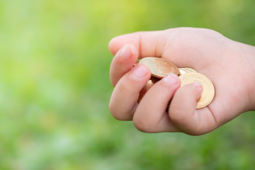 Money, Financial,Saving, Business Growth concept, Closeup of child holding golden coins in his hand on blurred background and copy space for text.