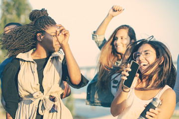 Smiling young women dancing and jumping together in park. Happy ladies listening music and dancing. Leisure concept