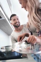 young husband and wife cook dinner together