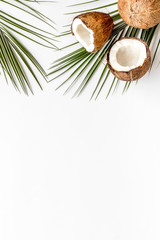 Fototapeta na wymiar Coconuts frame. Nuts pieces and exotic leaves on white background top-down copy space