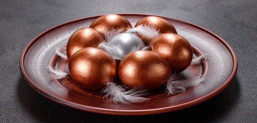 Easter eggs gold and bronze and Easter cake on a dark background