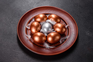 Easter eggs gold and bronze and Easter cake on a dark background