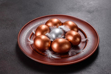 Easter eggs gold and bronze and Easter cake on a dark background