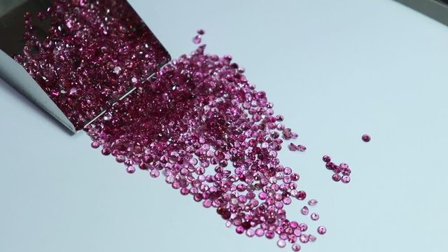 Shiny Pink sapphires with and stainless steel Stone Shovel for Loose Stones. Top view on white background. Gemstone background.