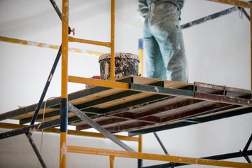 repair of premises, the builder works with plaster on scaffolding
