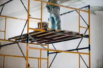 repair of premises, the builder works with plaster on scaffolding