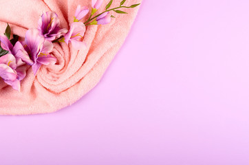 Spa concept idea,towel and flowers composition on purple background.