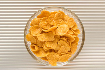 Cornflakes in a plate on a silver background. The view from the top.