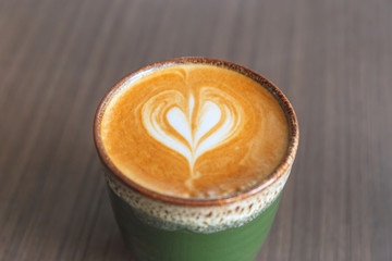 Selective focus of Hot latte art coffee in ceramic cup on blurred wooden table background