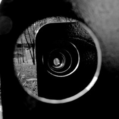 Black and white photo of metal plates with round holes. One after another.