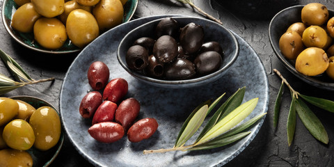 Olives panorama. An assortment of green, black and red olives on a dark background