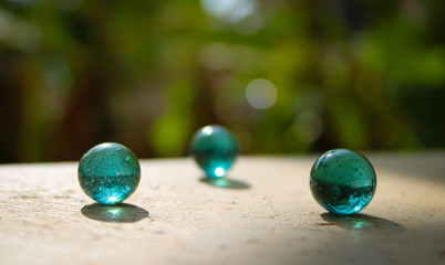 A transparent glass with green marbles on the top of the wall with a good blur background with a creative concept and  text area space.