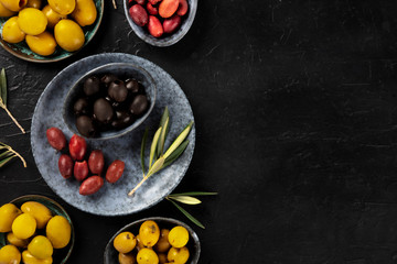 Olives, green, black and red, an assortment with leaves on a dark background with a place for text, shot from above