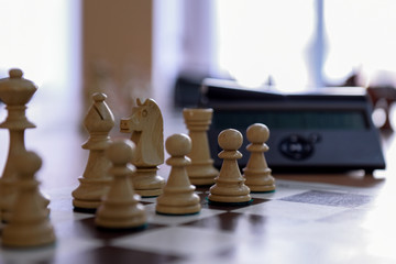 White chess pieces on the background of a chess clock.