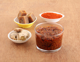 Ginger pickle, an Indian, vegetarian, and sweet and spicy side dish, with its main ingredients like ginger, jaggery, and red chili powder, in a glass jar.