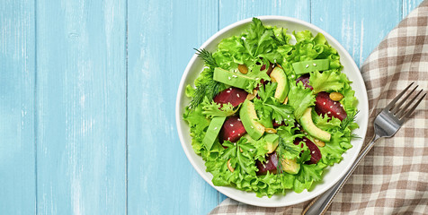 Vegan beetroot salad, avocado, lettuce, sunflower, sesame seed. Home made vegetarian beet salad. Clean eating concept on wood background. Tasty fresh beetroot veg mix leaves dish. Top view.