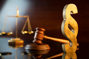 Law and justice concept. Judge’s gavel, scale and paragraph sign on the shining wooden brown...