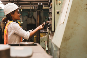 Fototapeta na wymiar Industry maintenance engineer woman dark skin wearing uniform and safety helmet under inspection and checking production process on factory station by tablet. Industry, Engineer, construction concept.