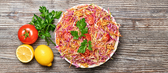 Vegan salad with red cabbage, cherry tomatoes, carrot, walnut. Home made vegetarian food. Clean eating concept on wood background. Tasty mix vegetable fresh cabbage salad. Top view.